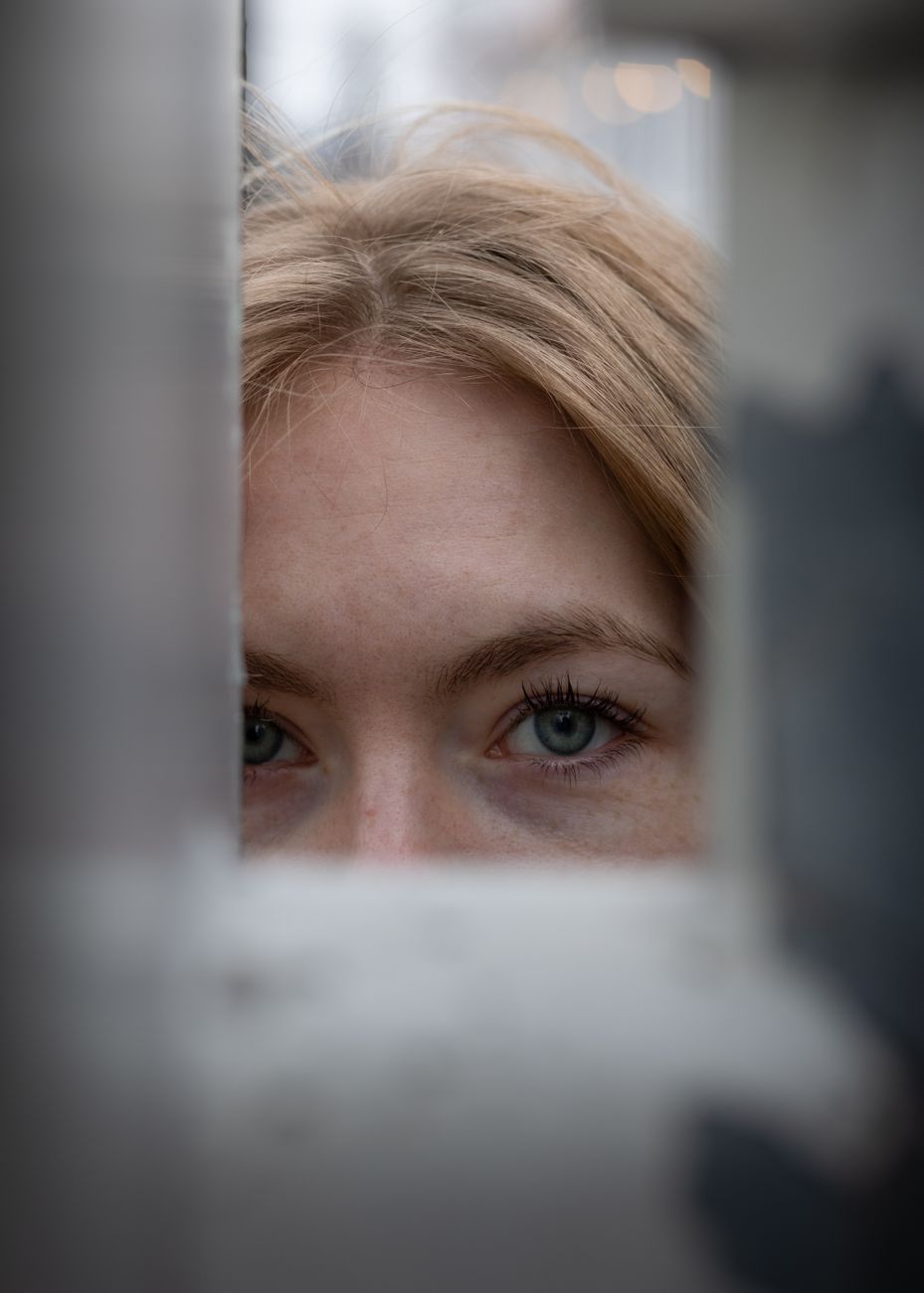 face of blonde woman peeking behind bars